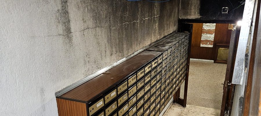 Portal de edificio con techo negro de hollín y daños por incendio