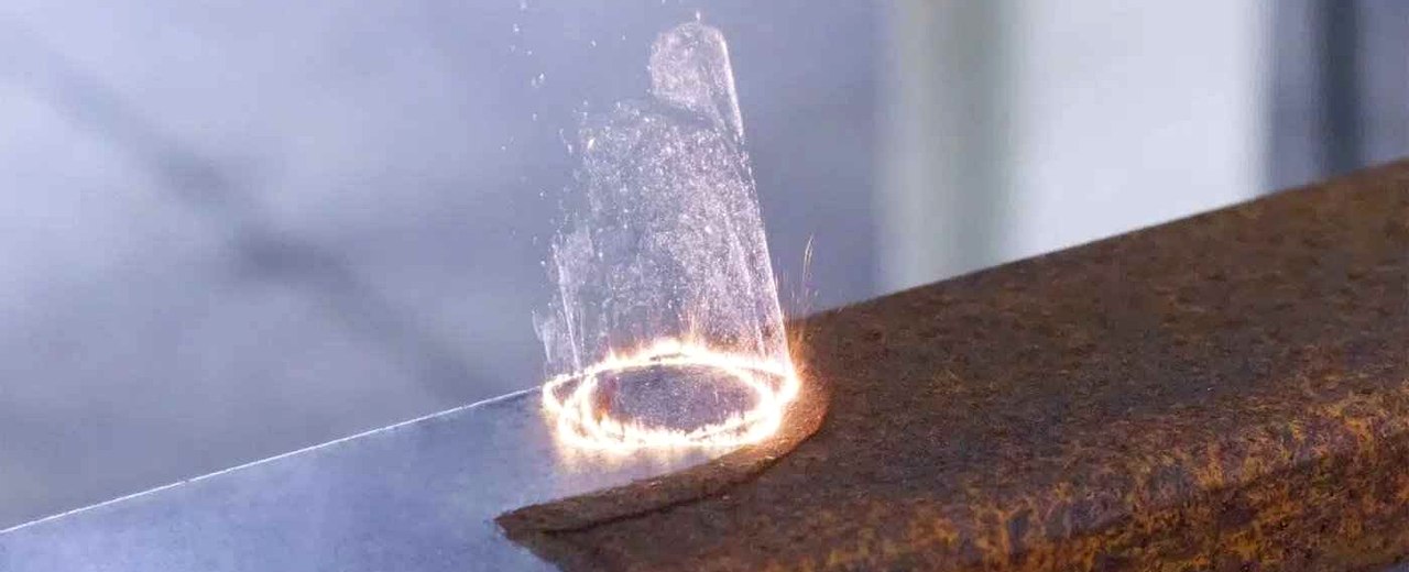 Limpieza láser — haz de luz eliminando óxido y hollín en metal con efecto espectacular