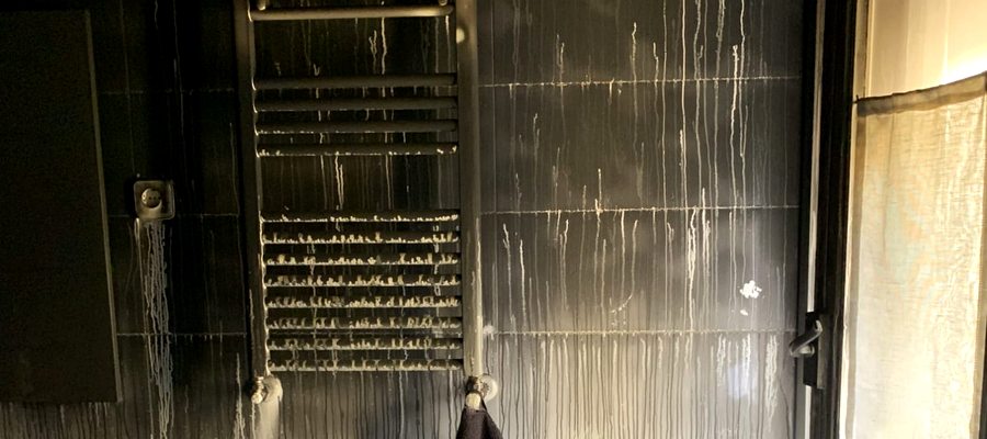Baño con hollín negro en paredes y azulejos tras incendio grave
