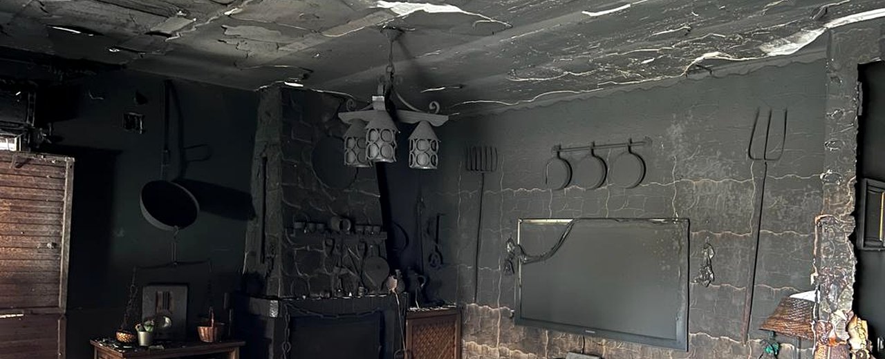 Salón completamente destruido por incendio grave — hollín en techo y paredes